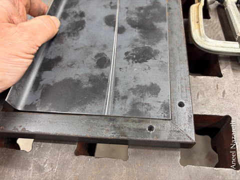 The sheet metal isn't folded. The edges of the sheet are flush with the insides of the bar, showing the miter and the corner